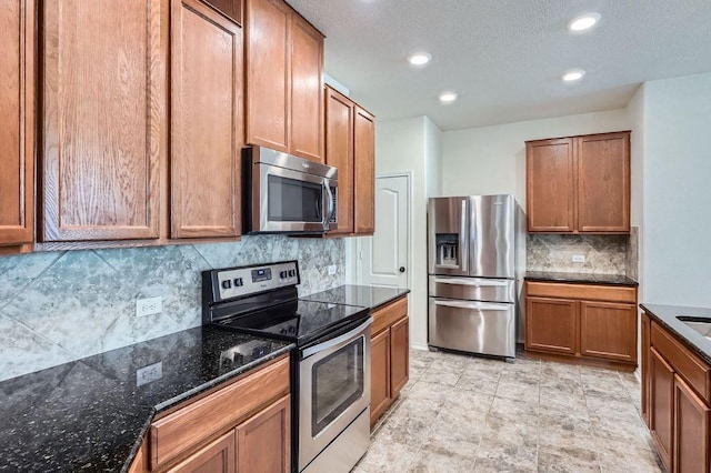 1161 Verna Brooks Way, Kyle, TX 78640 - kitchen featuring stainless steel appliances, decorative backsplash, brown cabinets, dark stone counters, and recessed lighting