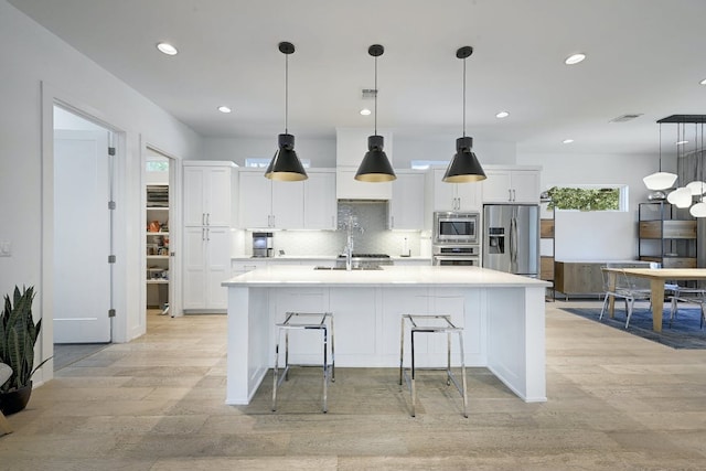 903 W Gibson St, Austin, TX 78704 - kitchen featuring stainless steel appliances, light wood-style flooring, white cabinets, recessed lighting, and an island with sink