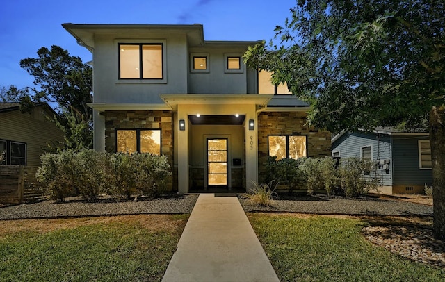 view of front of property with stone siding, a front yard, and stucco siding