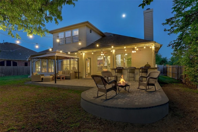 1218 Swenson Farms Blvd, Pflugerville, TX 78660 - back of house at night with an outdoor living space with a fire pit, a patio area, a chimney, and a gazebo