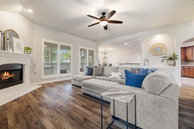 1218 Swenson Farms Blvd, Pflugerville, TX 78660 - living area with a ceiling fan, a warm lit fireplace, dark wood-style floors, a chandelier, and arched walkways