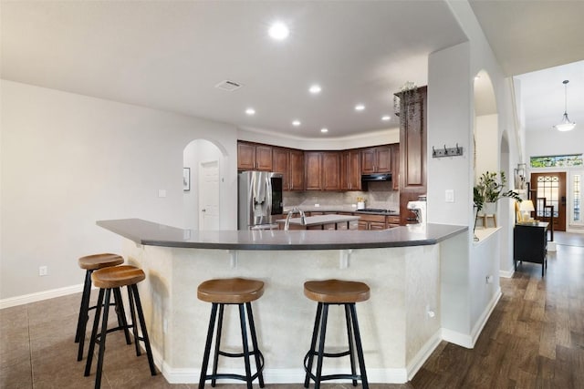 1218 Swenson Farms Blvd, Pflugerville, TX 78660 - kitchen featuring stainless steel fridge with ice dispenser, arched walkways, gas stovetop, tasteful backsplash, and a kitchen bar