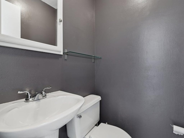 half bathroom featuring toilet and a sink