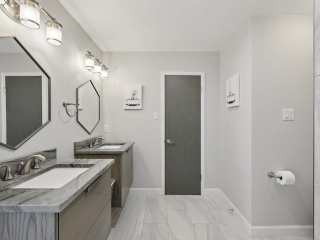 bathroom with two vanities, baseboards, marble finish floor, and a sink