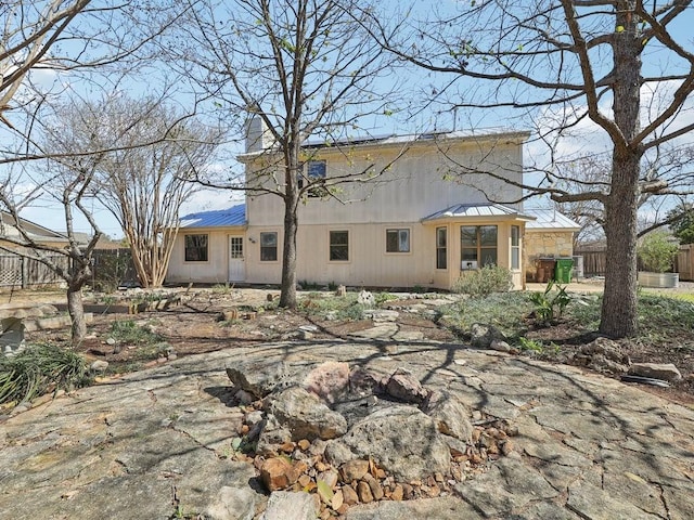 back of property featuring metal roof and fence
