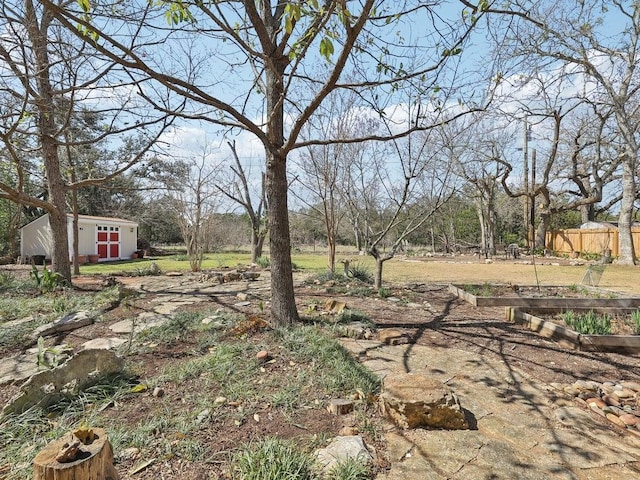 view of yard featuring a storage unit, fence, an outbuilding, and a garden