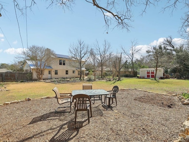 view of yard featuring a storage unit, fence, outdoor dining area, and an outbuilding