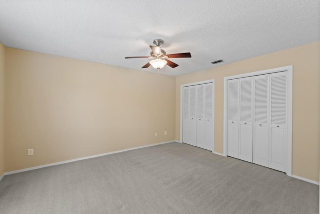 8112 W Ct, Austin, TX 78759 - unfurnished bedroom with multiple closets, carpet floors, baseboards, a ceiling fan, and a textured ceiling