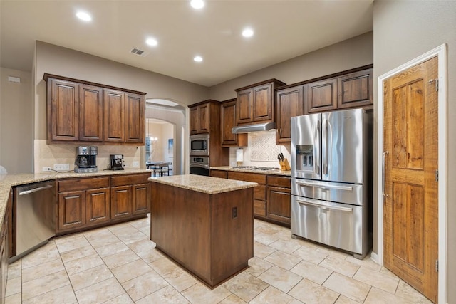 4105 Gandara Bnd, Austin, TX 78738 - kitchen featuring appliances with stainless steel finishes, arched walkways, decorative backsplash, under cabinet range hood, and recessed lighting