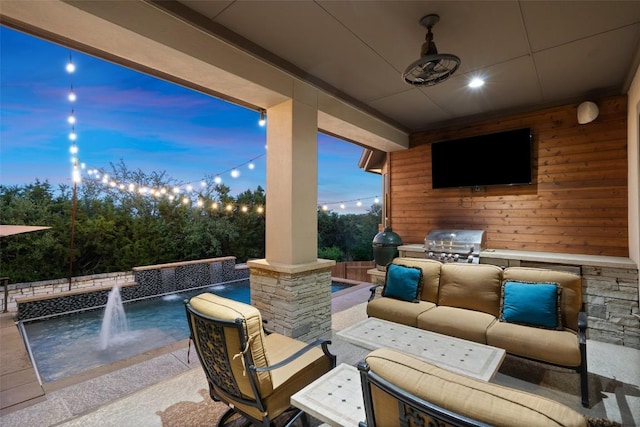 patio terrace at dusk featuring area for grilling, an outdoor kitchen, an outdoor hangout area, and a ceiling fan
