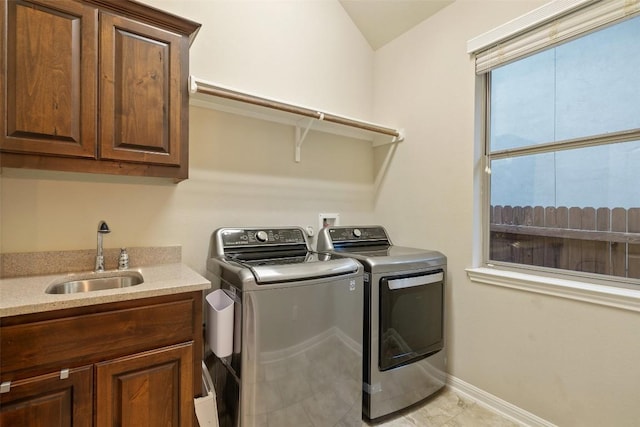 laundry room featuring baseboards, a sink, cabinet space, and washing machine and dryer