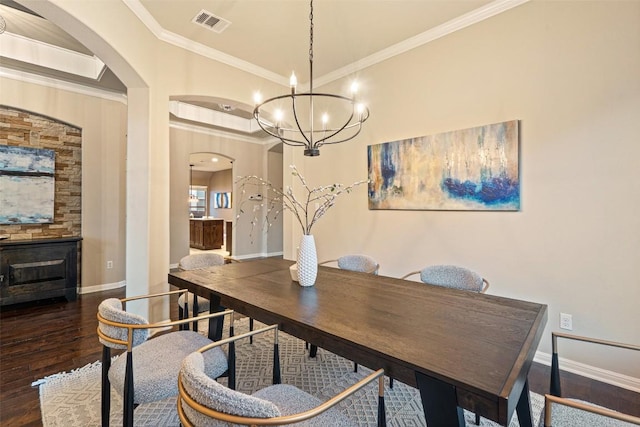 dining area featuring arched walkways, wood finished floors, ornamental molding, and visible vents