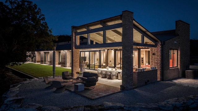 115 Seale Hill Rd, Comfort, TX 78013 - back of house at twilight featuring brick siding, a patio, a lawn, and a chimney