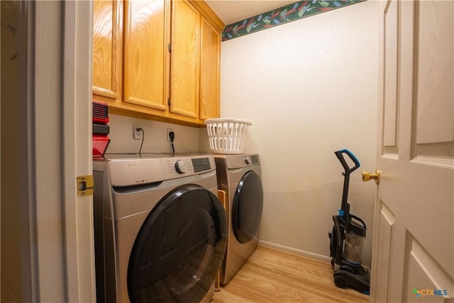 laundry area with light wood-style flooring, washing machine and dryer, baseboards, and cabinet space