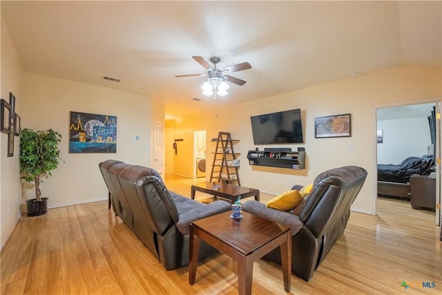 living room with visible vents, baseboards, a ceiling fan, light wood-style flooring, and washer / dryer