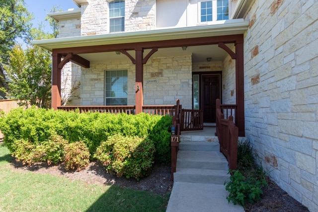 view of exterior entry with stone siding and covered porch