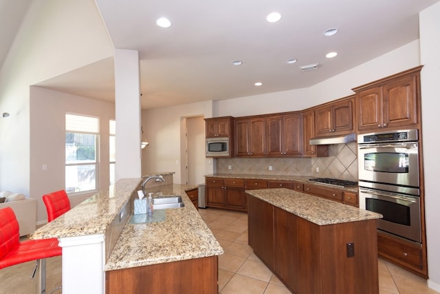 kitchen with stainless steel appliances, a center island, a sink, decorative backsplash, and light tile patterned floors