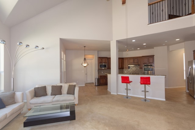 living room with baseboards, a high ceiling, light colored carpet, and light tile patterned floors