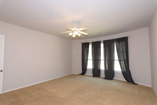 empty room with ceiling fan, visible vents, baseboards, and light carpet