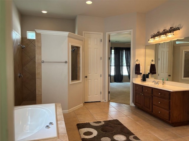 bathroom with a bathtub, tiled shower, baseboards, tile patterned flooring, and vanity