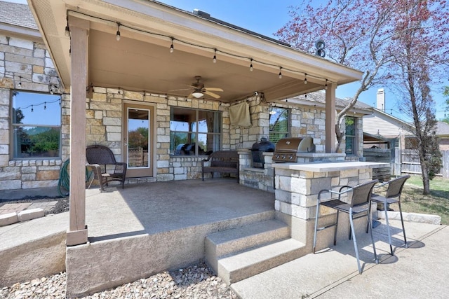 view of patio featuring a ceiling fan, an outdoor kitchen, area for grilling, and outdoor wet bar