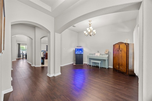 foyer featuring arched walkways, a notable chandelier, baseboards, and wood finished floors