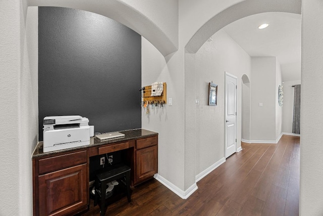 office space with dark wood-style flooring, baseboards, and arched walkways