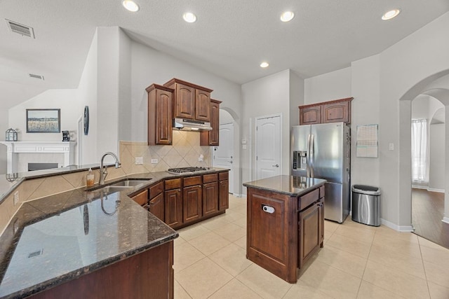 kitchen featuring arched walkways, under cabinet range hood, visible vents, and stainless steel appliances