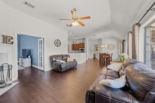 living room featuring wood finished floors, ceiling fan with notable chandelier, vaulted ceiling, and visible vents