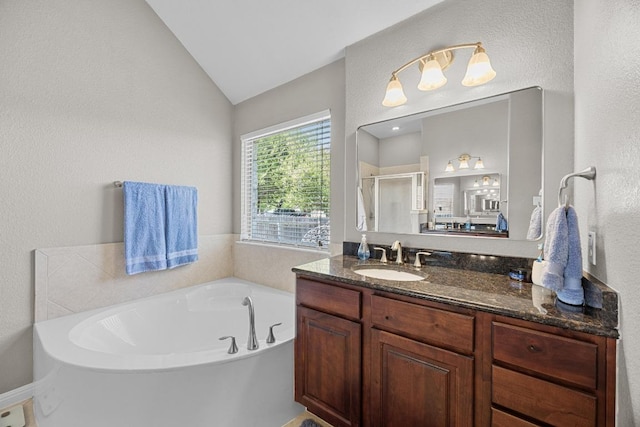 bathroom featuring a shower stall, a bath, vanity, lofted ceiling, and a textured wall