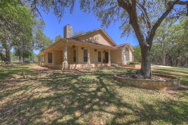 view of home's exterior with a yard, stone siding, covered porch, and a chimney