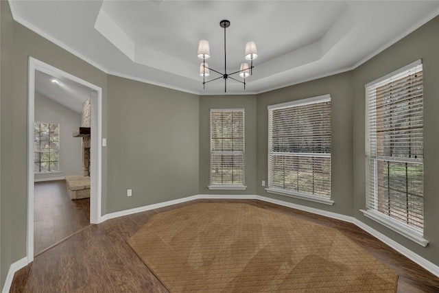 unfurnished dining area with dark wood-style floors, a notable chandelier, baseboards, and a tray ceiling