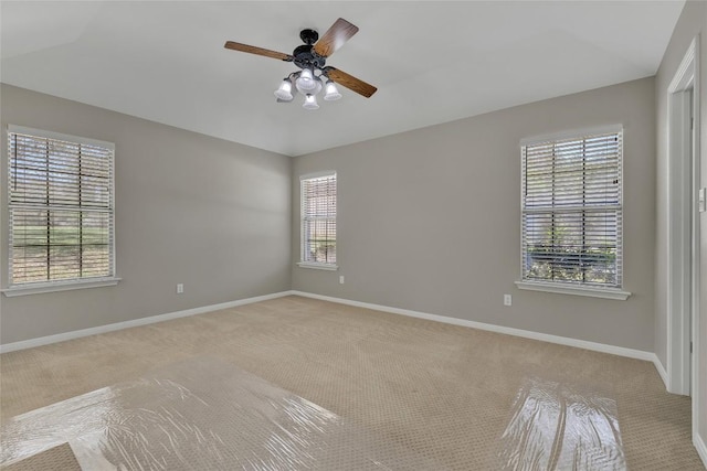 spare room featuring ceiling fan, light carpet, and baseboards