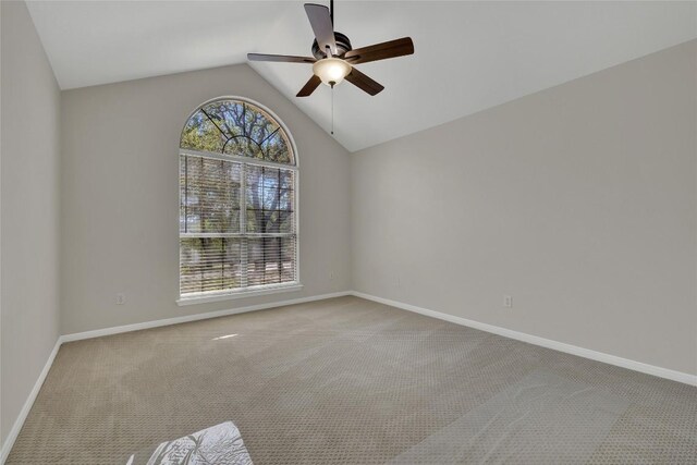 carpeted spare room featuring baseboards, ceiling fan, and vaulted ceiling