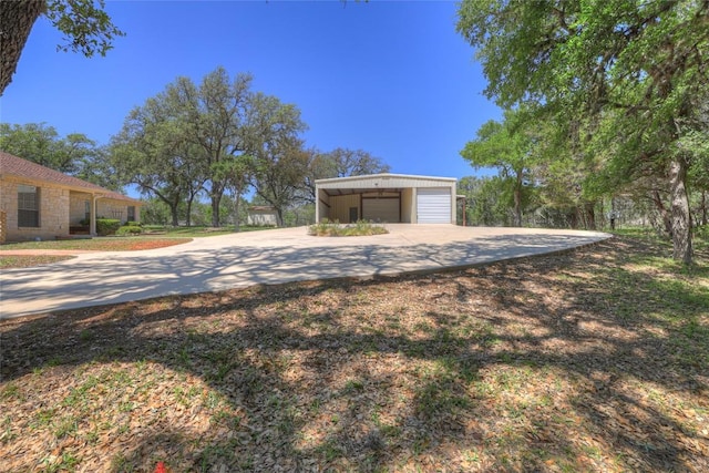 view of yard featuring an outdoor structure, a detached garage, and concrete driveway