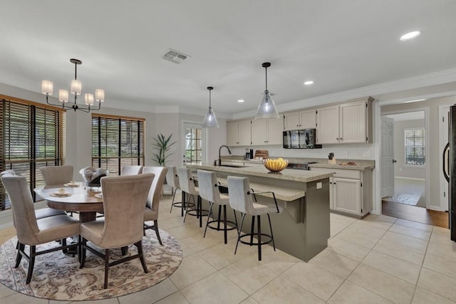 kitchen with light tile patterned floors, a sink, visible vents, black appliances, and ornamental molding