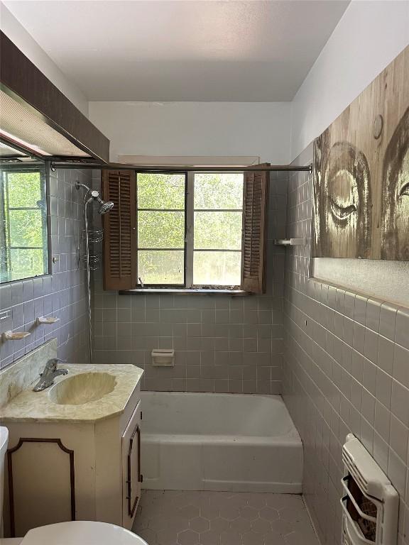 1006 Gilmore St, Taylor, TX 76574 - full bathroom featuring tile walls, tile patterned flooring, vanity,  shower combination, and heating unit