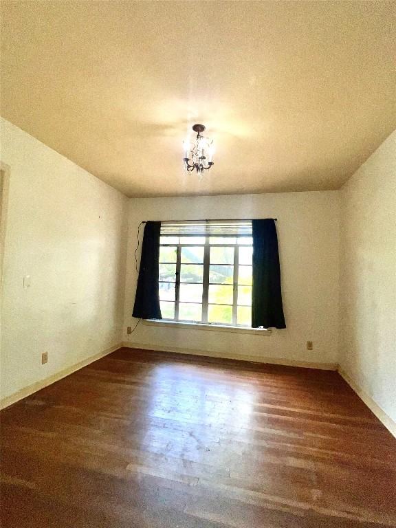 1006 Gilmore St, Taylor, TX 76574 - unfurnished room with wood finished floors, a chandelier, and a textured ceiling