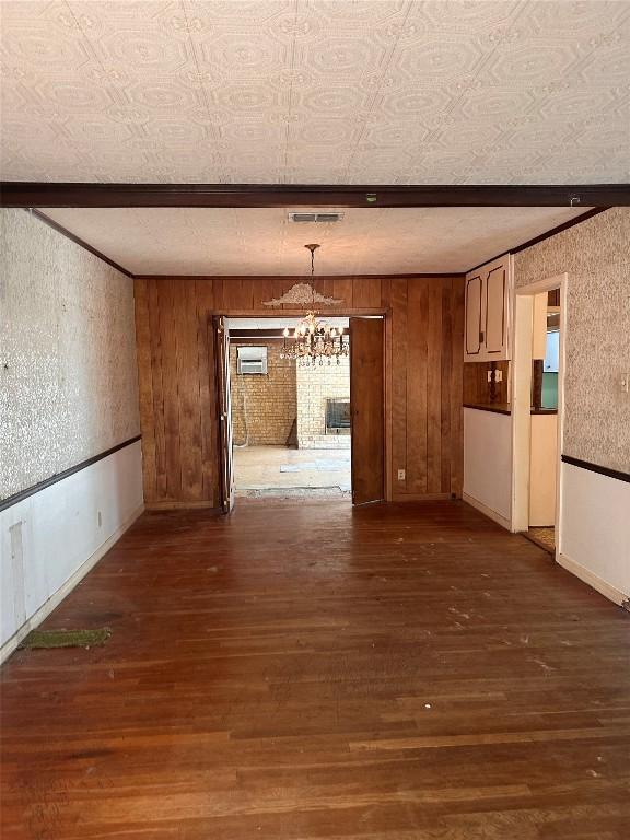 1006 Gilmore St, Taylor, TX 76574 - unfurnished dining area with a chandelier, dark wood finished floors, an AC wall unit, and wood walls
