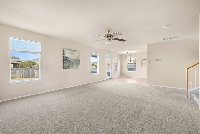 unfurnished living room featuring ceiling fan with notable chandelier, carpet flooring, baseboards, and visible vents