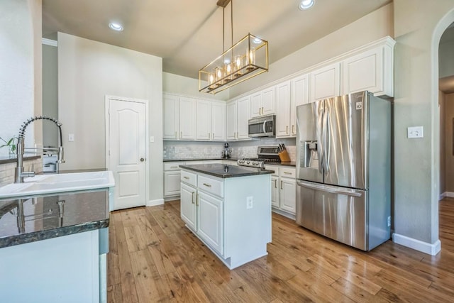 kitchen featuring tasteful backsplash, white cabinets, stainless steel appliances, arched walkways, and a sink