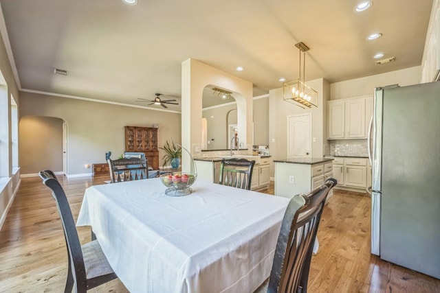 dining area featuring arched walkways, a ceiling fan, visible vents, recessed lighting, and light wood finished floors