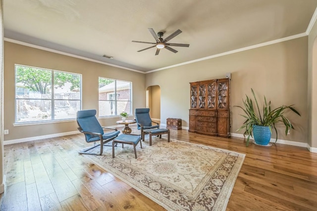 living area with arched walkways, wood finished floors, ceiling fan, and baseboards