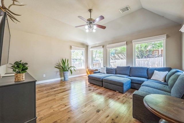 living area with a wealth of natural light, visible vents, light wood-type flooring, and lofted ceiling