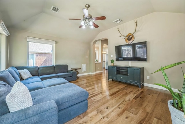 living room with visible vents, arched walkways, light wood-style floors, and lofted ceiling