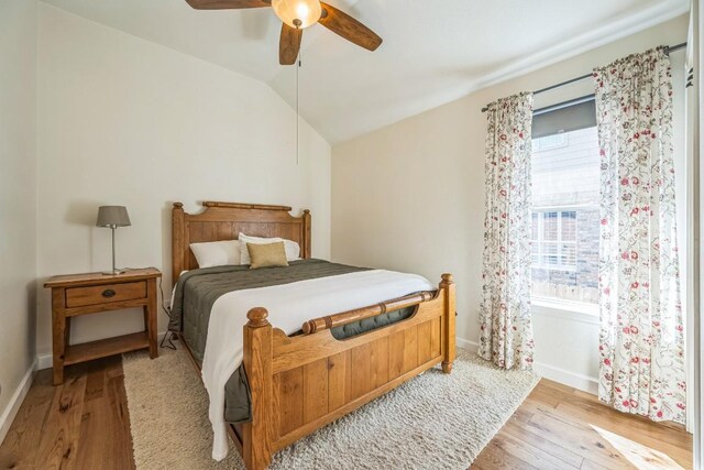 bedroom with lofted ceiling, ceiling fan, baseboards, and wood finished floors