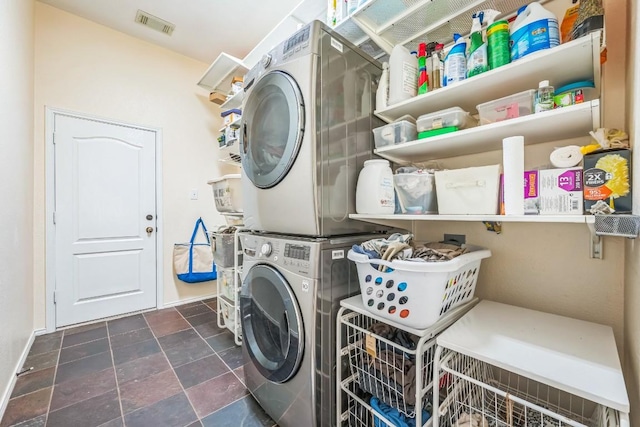 washroom with visible vents, baseboards, stone finish floor, stacked washer / dryer, and laundry area