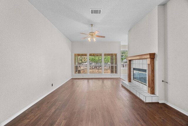 unfurnished living room featuring baseboards, visible vents, ceiling fan, a tile fireplace, and wood finished floors