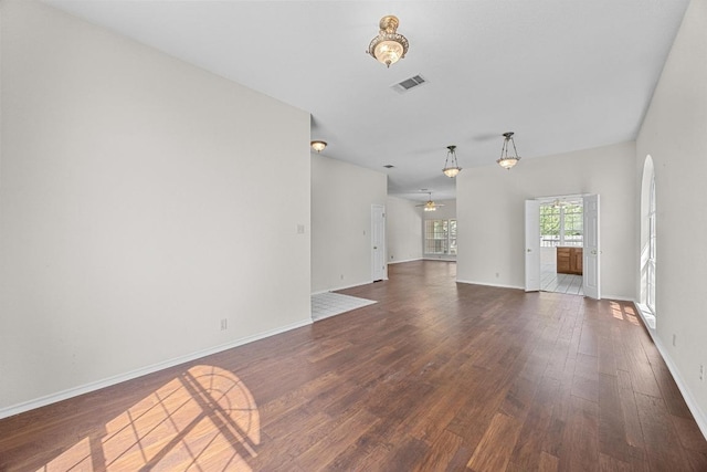 unfurnished living room with dark wood-type flooring, baseboards, a ceiling fan, and visible vents