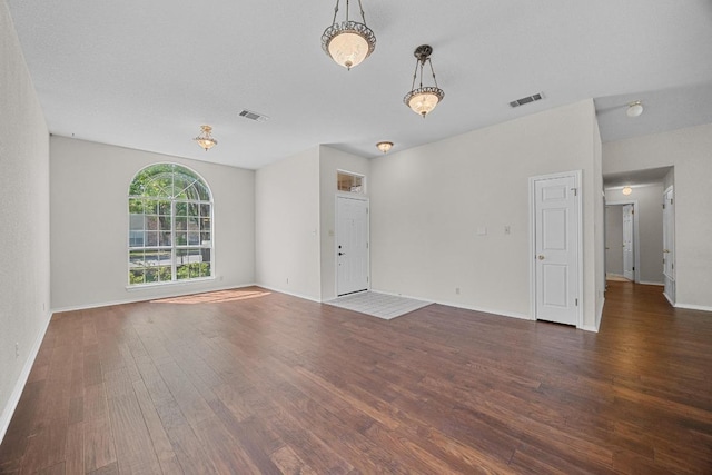 unfurnished living room featuring wood finished floors, baseboards, and visible vents